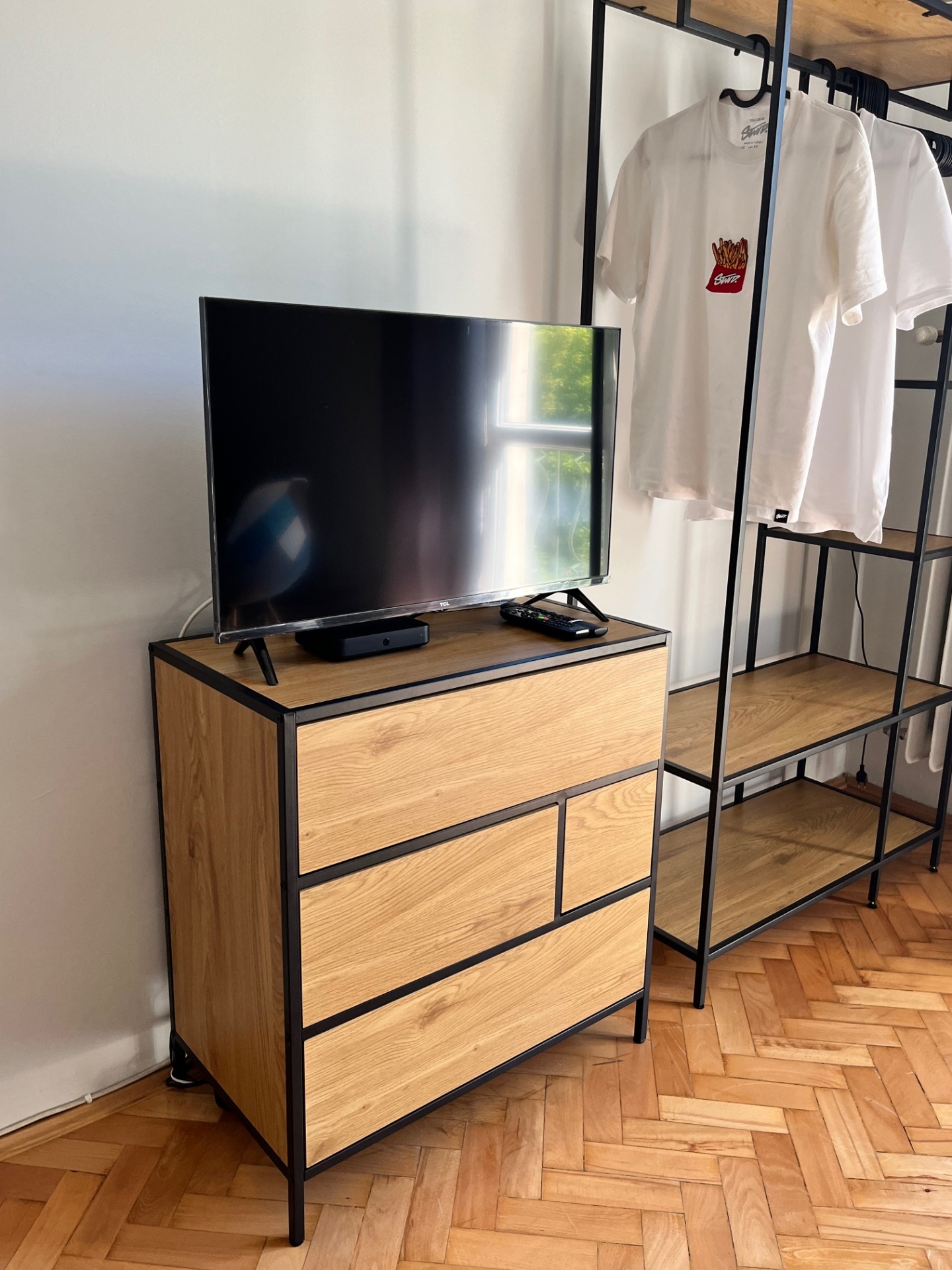 Telewizor na komodzie i wieszak na ubrania